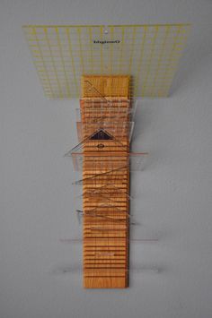 a clock made out of wood and wire on top of a white wall next to a gray wall