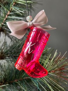 a christmas ornament hanging from a pine tree with a pink boot on it