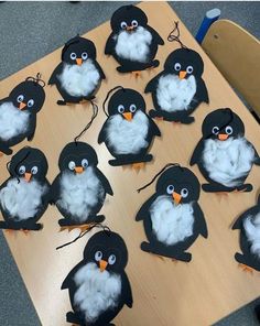 a bunch of penguins that are sitting on a wooden table with some string attached to them