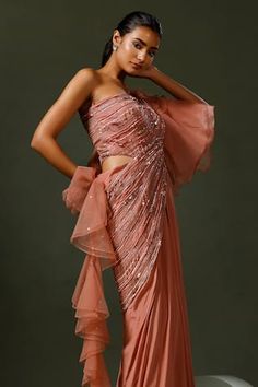 Pink asymmetric sleeves one shoulder saree gown encrusted with sequins, cutbeads, feather work and organza ruffled power sleeve on one side extending into ruffled drape.
Components: 1
Pattern: Embroidery
Type Of Work: Thread Work, Cut Dana, Sequin
Neckline: One Shoulder
Sleeve Type: Asymmetric Sleeves
Fabric: Crepe: Bottom , Net: Drape and Organza: Sleeves
Color: Pink
Other Details: 
Padded saree gown
Occasion: Cocktail - Aza Fashions Pre-draped Side Open Saree For Party, Party Pre-draped Floor-length Lehenga, Designer Saree Dress With Draped Sleeves, Evening Saree Dress With Draped Sleeves, Party Pre-draped Saree With Cape Sleeves, Pre-draped Embellished Festive Gown, Party Wear Saree With Cape Sleeves, One Shoulder Fitted Saree, Embellished One-shoulder Evening Saree