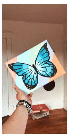 a hand is holding up a box with a blue butterfly on it