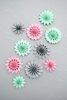 six different colored paper flowers on a gray surface