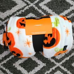 an orange and white diaper with pumpkins on it sitting on the floor next to a tag