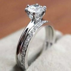 a close up view of a diamond ring on a white cloth with wood floor in the background