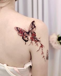 the back of a woman's shoulder with a butterfly and flowers tattoo on it