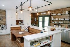 a kitchen with wooden walls and white cabinets is shown in this image, there are lights hanging from the ceiling