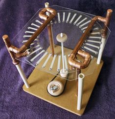 a clock made out of pipes sitting on top of a purple blanket