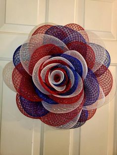 a red, white and blue flower hanging from a door