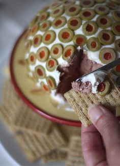 a person is cutting into a cake with chocolate and fruit toppings on the top