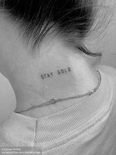 a woman's neck with the word stay gold tattooed on her left side ribcage