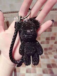 a hand holding a black dog shaped keychain on it's wrist with a chain attached to it