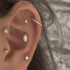 a woman with three different ear piercings on her left ear and one is wearing a diamond