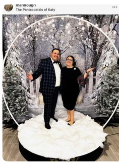 a man and woman posing for a photo in front of a snow scene with trees