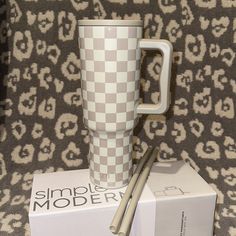 a white and grey checkered coffee cup next to a box