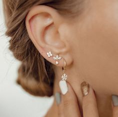 This set consists of four separate earrings, in three different styles, all made from sterling silver and embellished with zirconia stones. It has: 🌟 One stud earring with four tiny zirconia arranged in a flower shape; 🌟 One stud earring with three marquise-cut zirconia arranged in a fan shape with one small round zirconia hanging beneath; 🌟 One pair of huggie hoop earrings with a flower shaped charm hanging from their lower edge, decorated with six round zirconia. A feminine and elegant set Earrings 3 Lobes, 3 Piercings Ear Studs, Jewelry Wedding Earing Multi Holes, Three Earlobe Piercings, Flower Earrings With Diamond Accents In Cubic Zirconia, Flower Shaped Earrings With Diamond Accents, Gold Fine Jewelry Cluster Earrings, Yellow Gold Flower Earrings Fine Jewelry, White Gold Flower Earrings