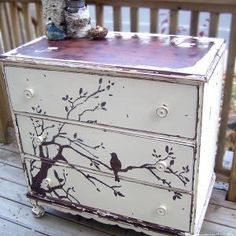 an old dresser has birds painted on it and is sitting on a deck with other items