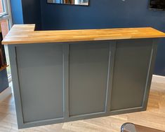 a kitchen island with wooden counter top in front of blue walls and hardwood flooring