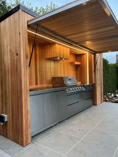 an outdoor kitchen is built into the side of a wooden building with a grill on it