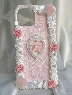 a pink and white phone case with roses on it's side, in the shape of a heart