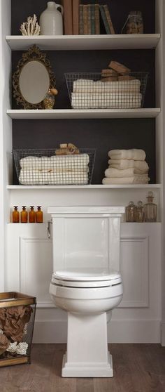 a white toilet sitting inside of a bathroom next to a shelf filled with towels and other items