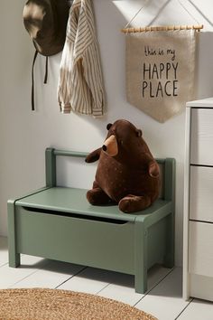 a teddy bear sitting on top of a green bench in front of a white wall