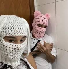 two people wearing crocheted masks in the bathroom