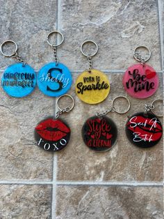 six different key chains with the words sorry to sparkle written in red, yellow and blue