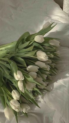 a bouquet of white tulips laying on a bed