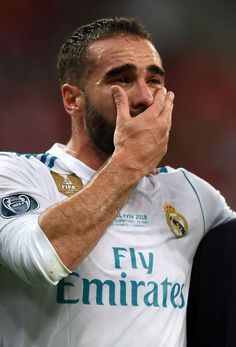 the soccer player is wiping his face while holding his hands to his mouth and looking at the camera