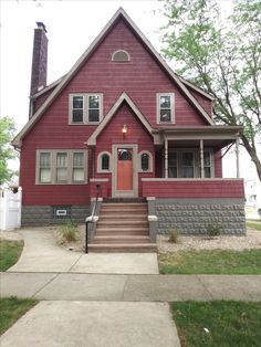 a red house with stairs leading up to the front door