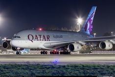 a large jetliner sitting on top of an airport tarmac at night with its lights on