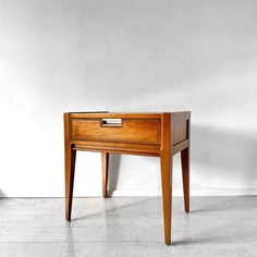 a small wooden table with one drawer on the top and two drawers on the bottom