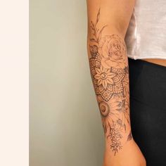 a woman's arm with tattoos on it and flowers in the middle of her arm