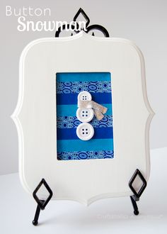 a white frame with two snowmen in it and the words button snowman written below