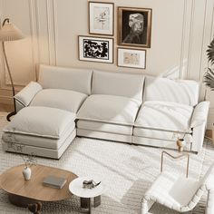 a living room filled with white furniture and pictures on the wall above it's coffee table