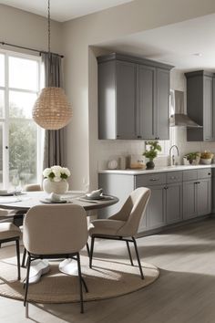 a dining room table surrounded by chairs in front of a kitchen with gray cupboards