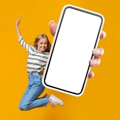 a woman jumping in the air while holding up a cell phone with a white screen