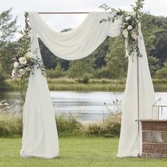 an outdoor wedding setup with white drapes and flowers