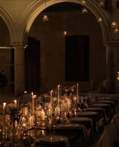 a long table is set with candles and flowers for a formal dinner or function in an old building