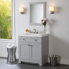 a bathroom with a sink, mirror and trash can on the floor next to it