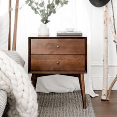 a bedroom with white walls and wood furniture