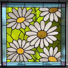 a stained glass window with white daisies on green and gold foiled backings