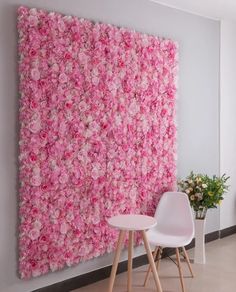 pink and white flowers on a wall in an office setting with two chairs next to a table