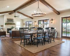 a dining room table and chairs in front of a fireplace with french doors leading into the living room