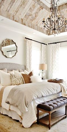 a bedroom with a bed, mirror and chandelier hanging from it's ceiling