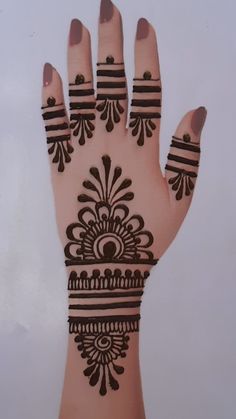 a hand with henna on it that has stripes and circles around the wrist area