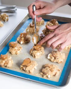 a person is cutting cookies on a cookie sheet with a spatula and some peanut butter