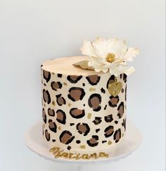 a leopard print cake with a white flower on the top and gold lettering that says,