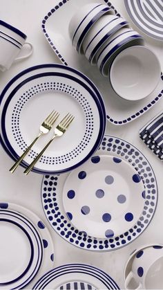 a table topped with plates and silverware next to a white plate covered in blue polka dots