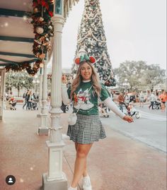 a woman standing next to a pole in front of a christmas tree